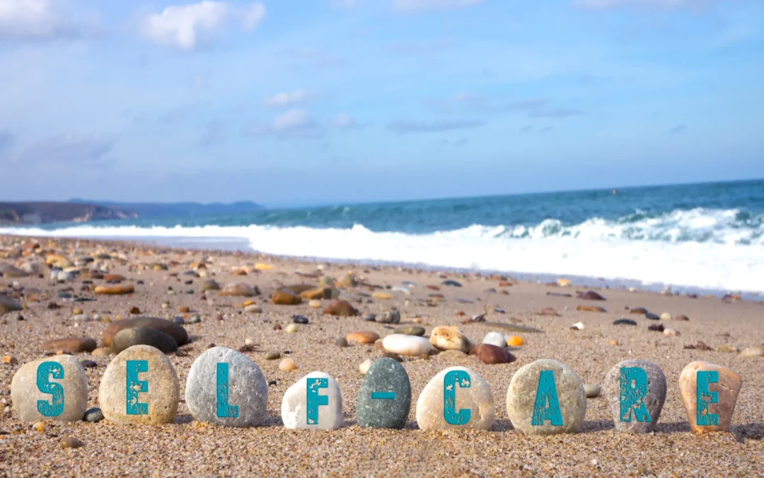 Self-care written in stones on the beach
